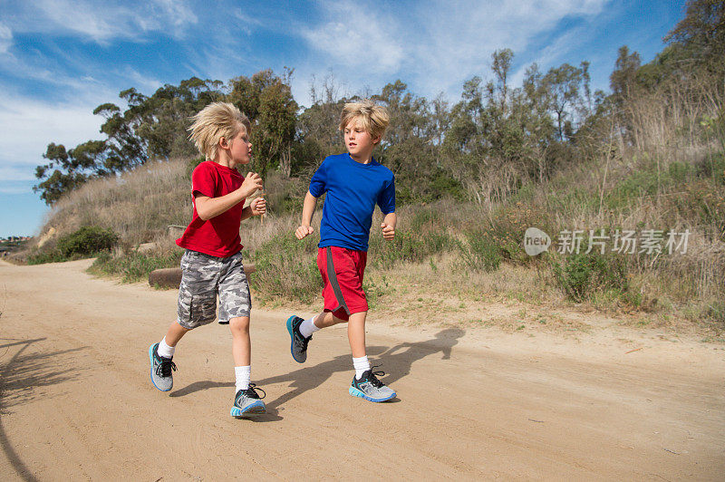 两个孩子在泥土路上沿着泻湖奔跑