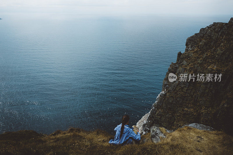 在挪威徒步旅行和看海后带着狗休息的女人