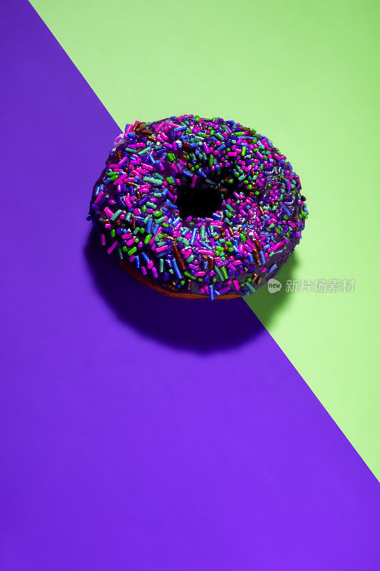 明亮的波普艺术甜甜圈在绿色紫色对角线背景