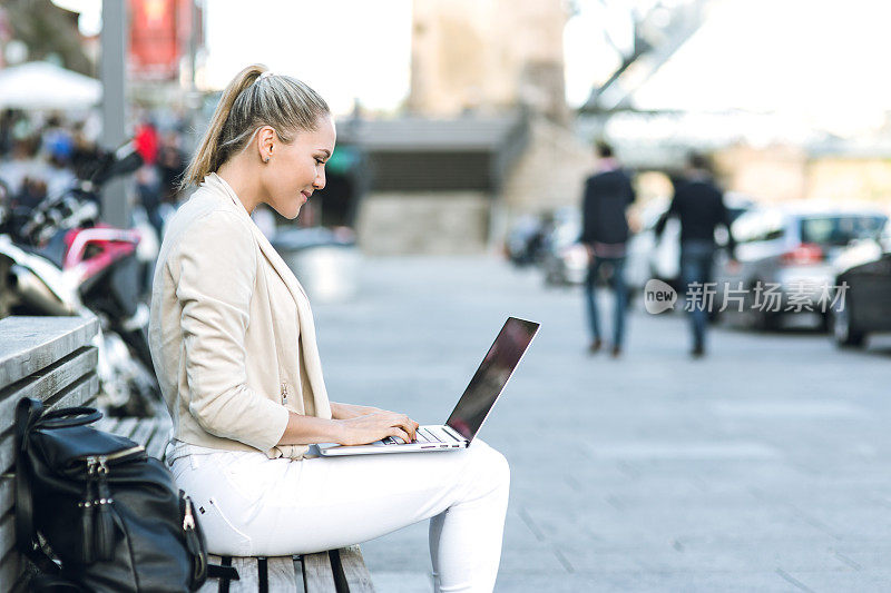 一个女人在街上用笔记本电脑
