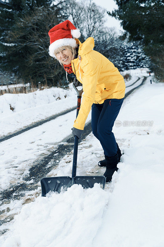 老妇人正在用雪铲清理积雪