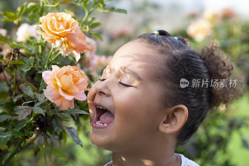 快乐的小女孩闻着玫瑰。