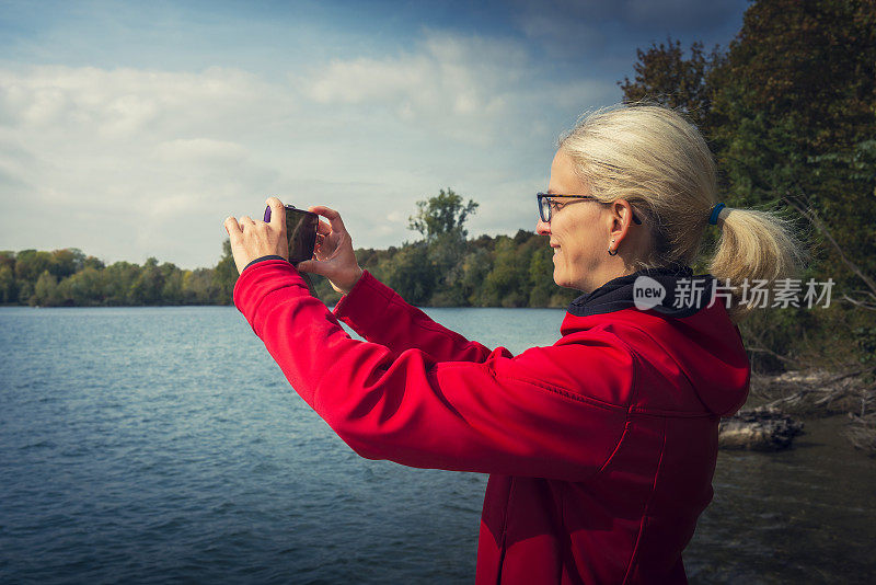 一个拿着数码相机在湖上自拍的女人