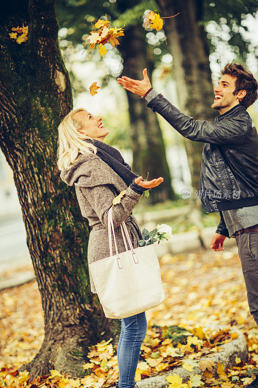 快乐的情侣在秋天扔枫叶玩