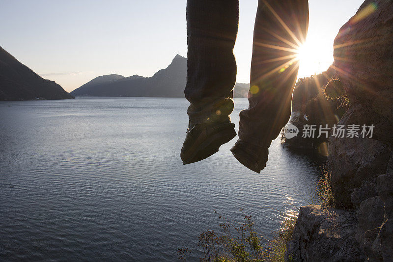 徒步旅行者把腿悬在湖面上