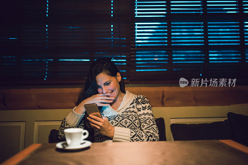 年轻女性喜欢喝咖啡休息时间。她在咖啡馆用手机。