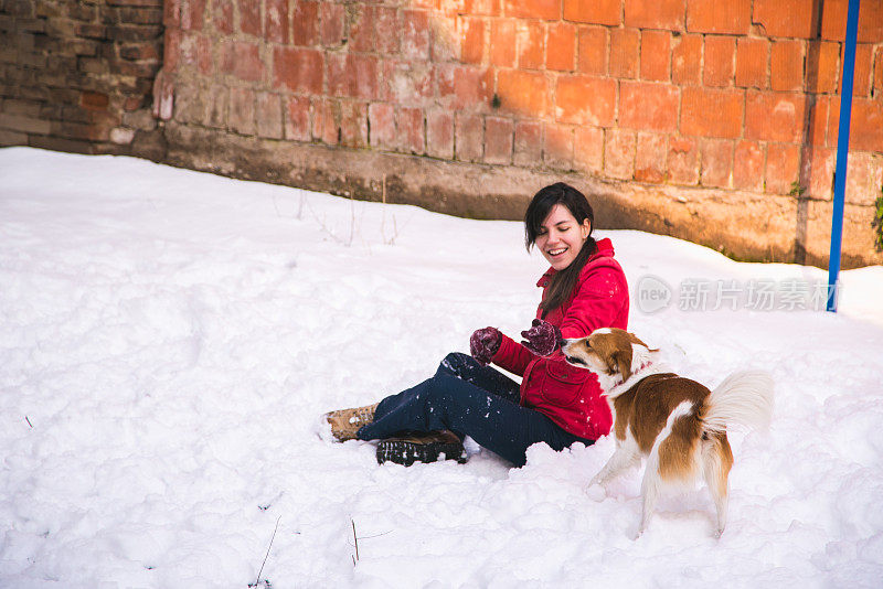 一个女人在雪里和狗玩