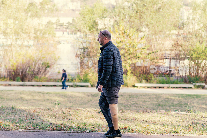 一个戴着假肢的成年人正在城市公园里散步