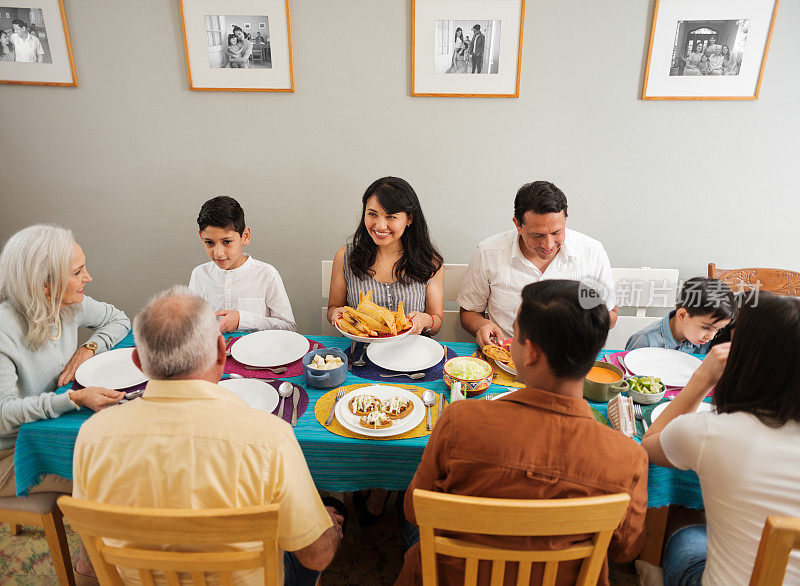 几代墨西哥家庭围坐在餐桌前吃着食物