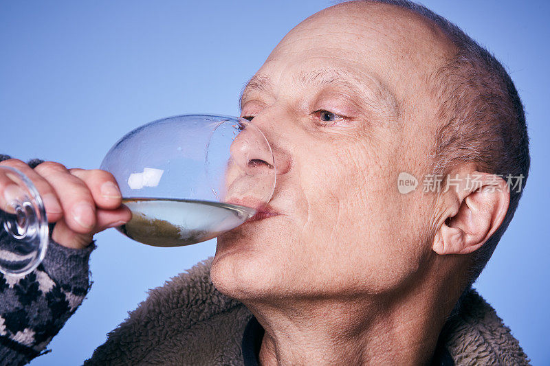 一个成熟的男人仰着头，欣赏地啜饮着白葡萄酒