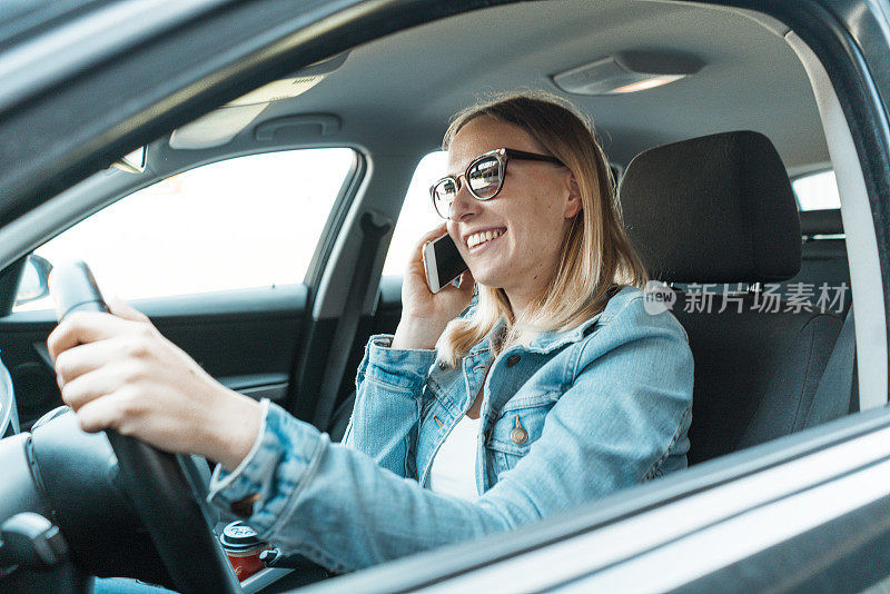快乐的年轻女人一边开车一边打电话