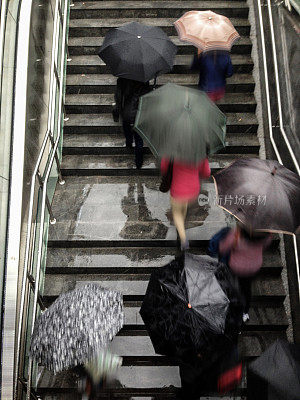 地铁楼梯上撑着雨伞的人们的鸟瞰图