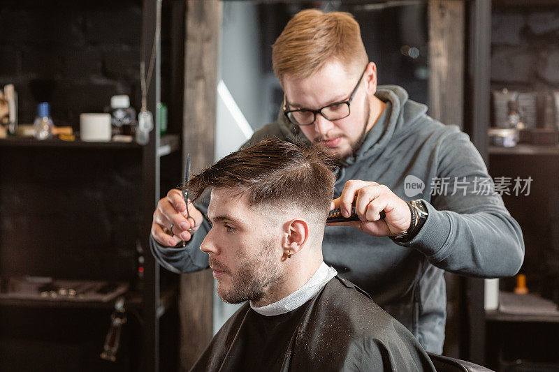 用金属剪刀剪头发。师傅在理发店里为男人理发和刮胡子，美发师为年轻人做发型