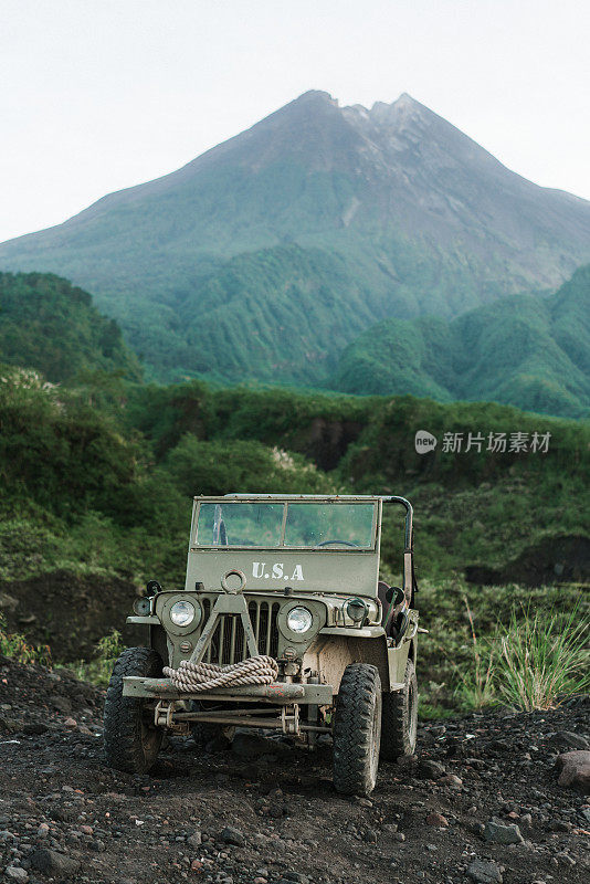 在默拉皮火山的背景上老式SUV的风景