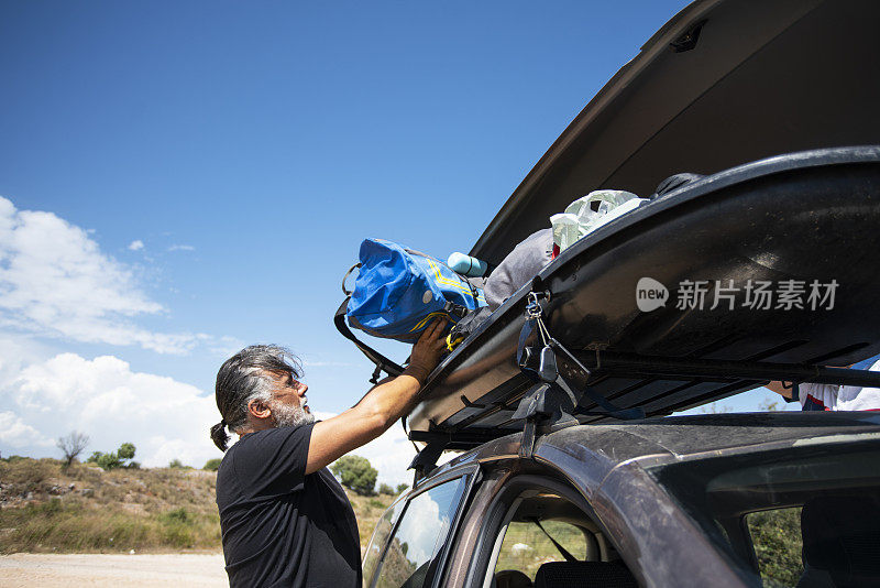 度假的男人在屋顶行李架上打包货物箱集装箱