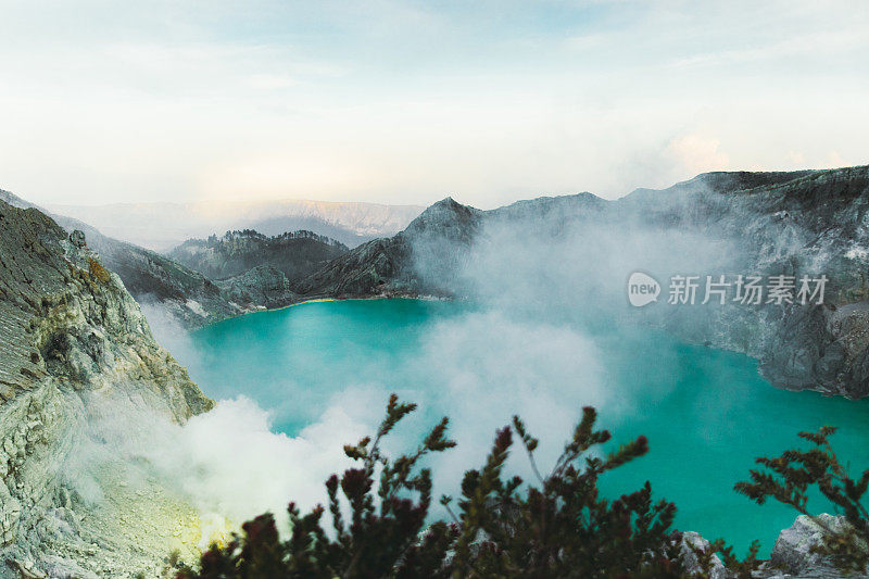 印度尼西亚东爪哇的伊真火山火山口的绿松石色湖泊，山脉和硫磺蒸汽的戏剧性景色