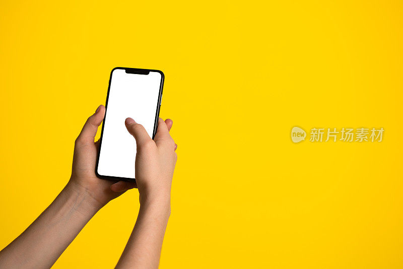 一个手持无边框智能手机的特写黄色背景