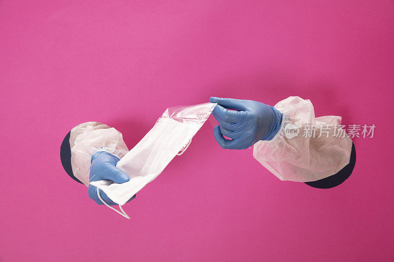 双手握着，粉红色背景上显示外科口罩。