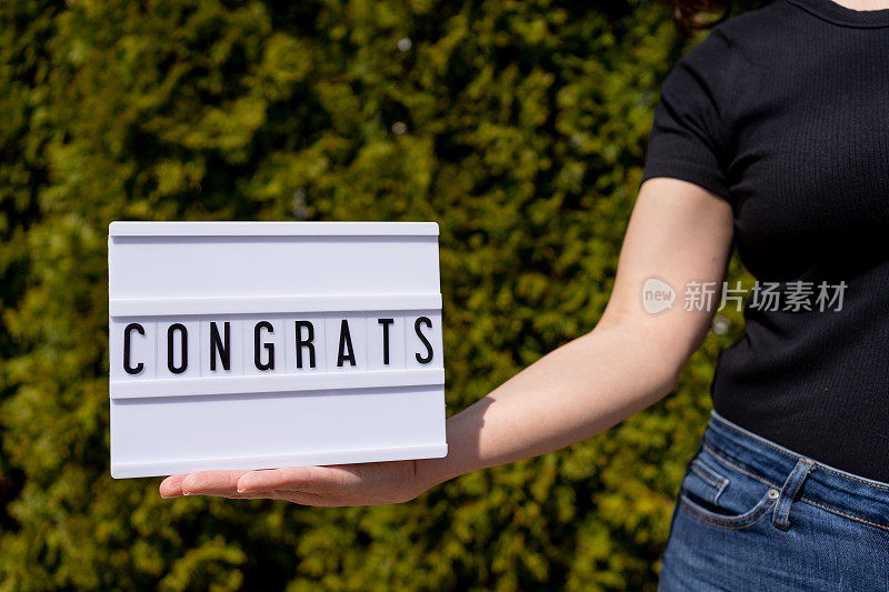 女子举着写着“恭喜”的牌子