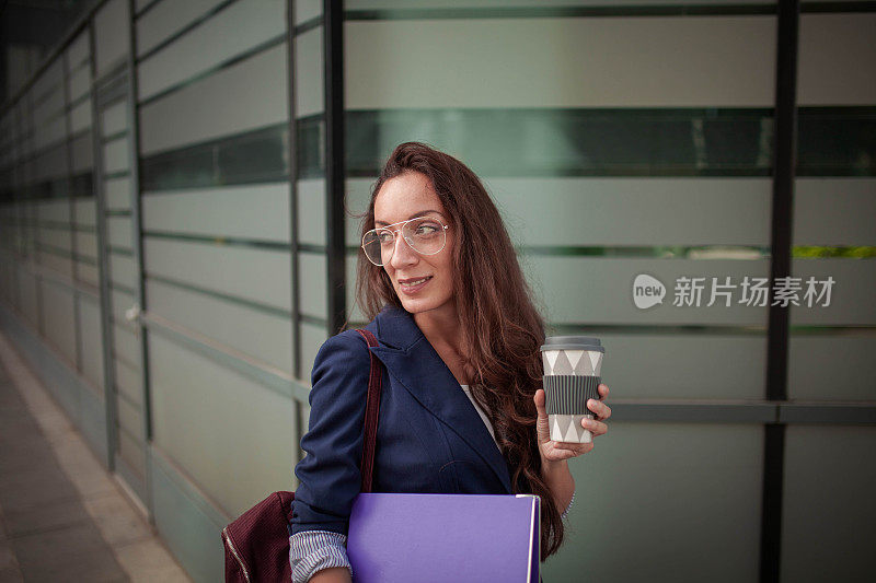 年轻的女商人拿着一杯咖啡