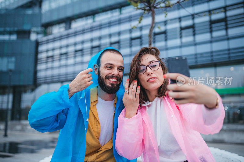 一对穿着雨衣的年轻漂亮的夫妇正在拍视频