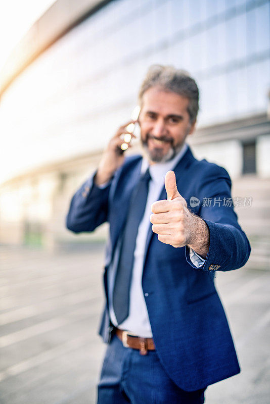 快乐成熟的商人在电话里竖起大拇指。