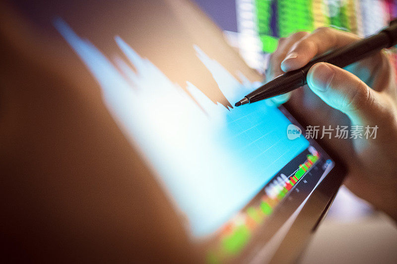 商人检查股票市场的数字平板电脑和台式电脑与股票交易图形屏幕上。金融股票市场。办公后台数据分析。