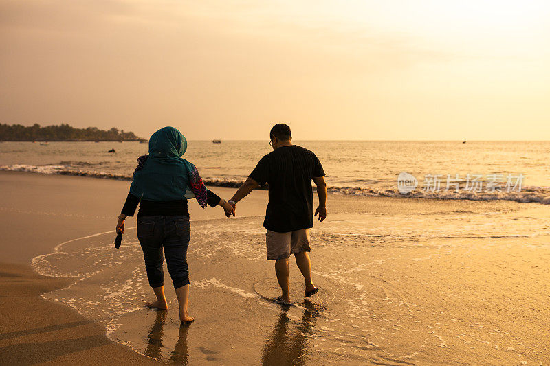 在海滩上牵着手的幸福夫妇