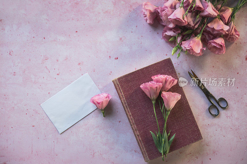 粉色的洋桔黄色花，信封和一本书