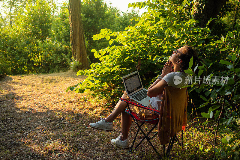 在大自然中使用笔记本电脑的年轻女性