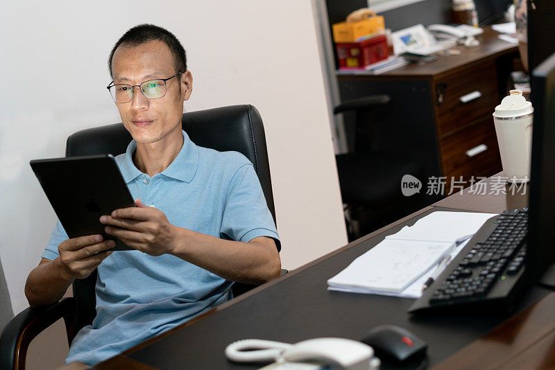 中国男性白领在办公室里举着平板电脑的肖像。