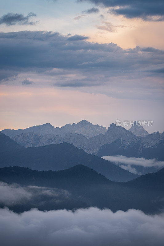 晚上在意大利Dolomites。多层远处的山峰渐渐消失在背景中，在图像的底部形成了云的反转。
