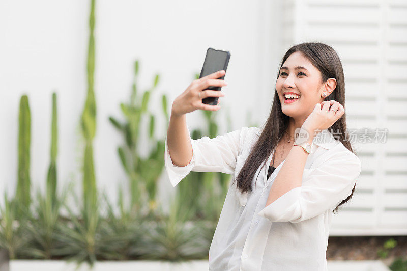 年轻的亚洲美女用智能手机自拍。