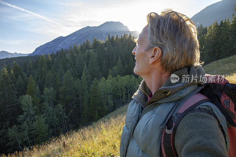 日出时，男性徒步者沿着森林小径行走