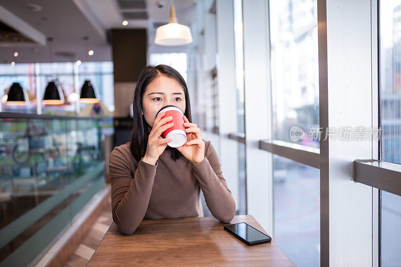 年轻的亚洲女性在咖啡店里使用智能手机