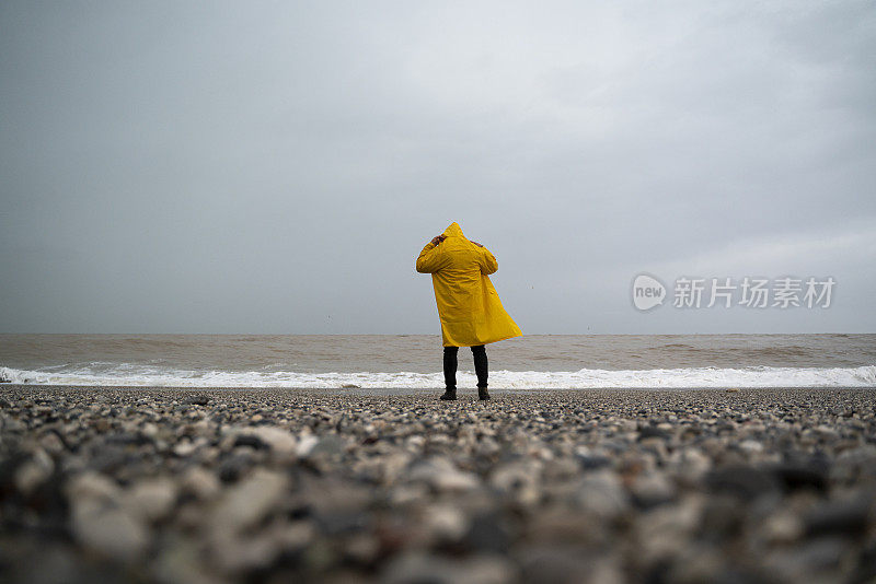 土耳其安塔利亚，一个下雨天，一名身穿黄色雨衣的男子在海滩上