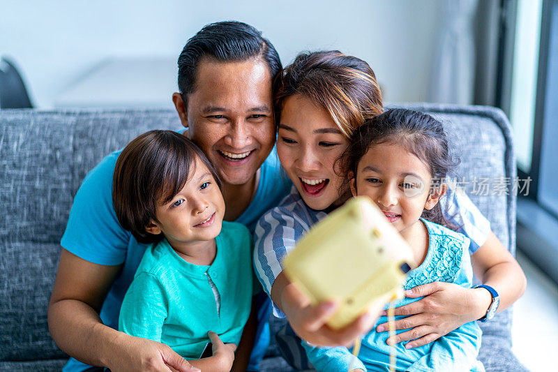 年轻的混血儿亚洲家庭在家里与一个宝丽来相机。