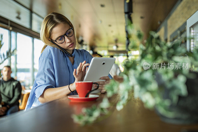 一个非常有魅力的年轻女商人正在Café享受热饮，并在她的手机对话中制定一些商业计划。