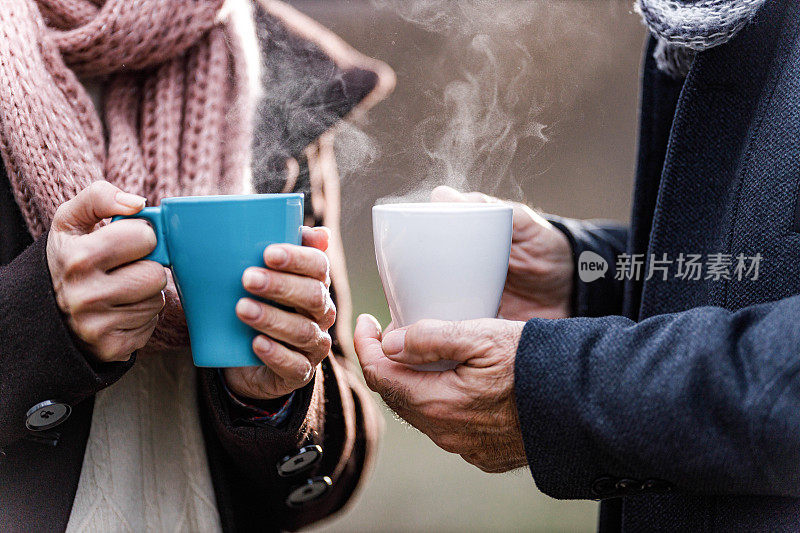 近距离观察一对老年夫妇在大自然中喝热饮。