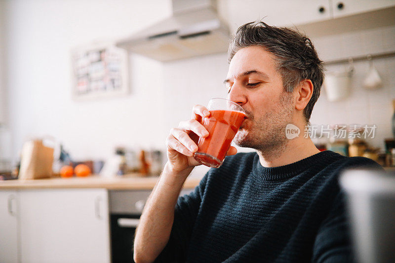 一个男人在家里吃水果奶昔当早餐