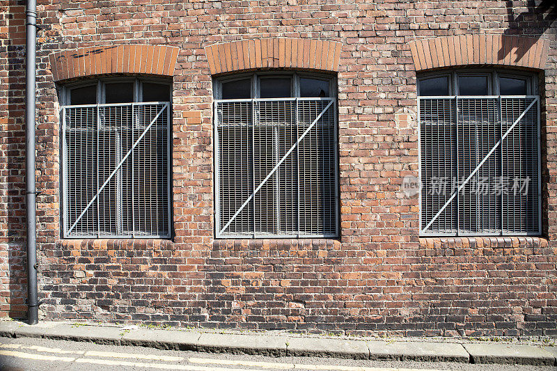 从街上可以看到，旧砖墙上的三扇大窗户上覆盖着金属安全屏