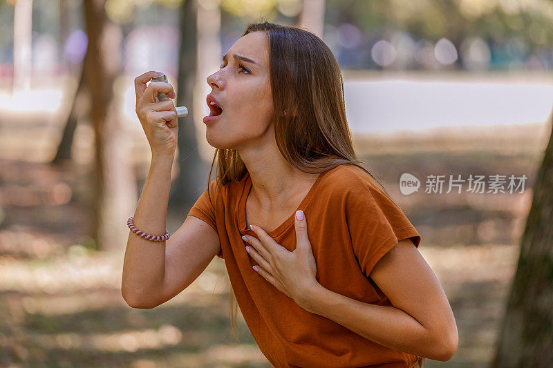一名妇女在公园里使用哮喘吸入器。