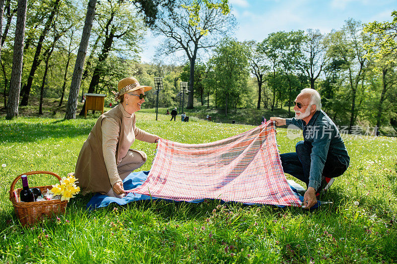 一对老年夫妇在公园里铺毯子