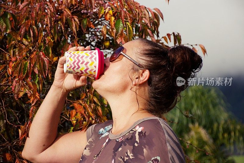 女人用可重复使用的咖啡杯喝咖啡