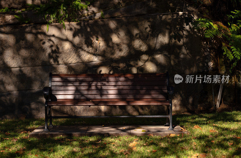 斑驳的阳光下的木制公共长椅