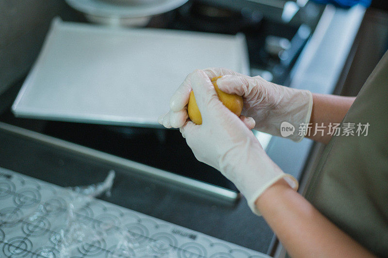 一位亚洲华人妇女在家里揉着食谱中的配料