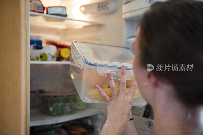 年轻女子从冰箱里拿生食物