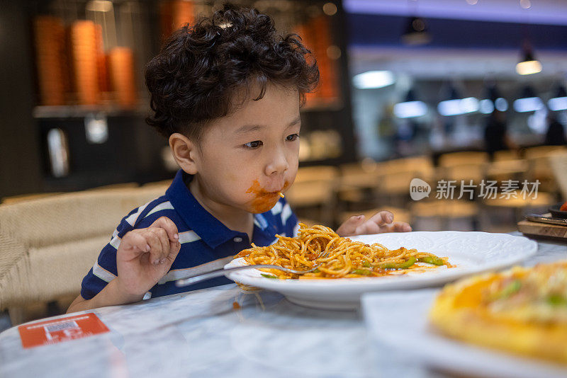 一个小男孩在餐馆里吃意大利面