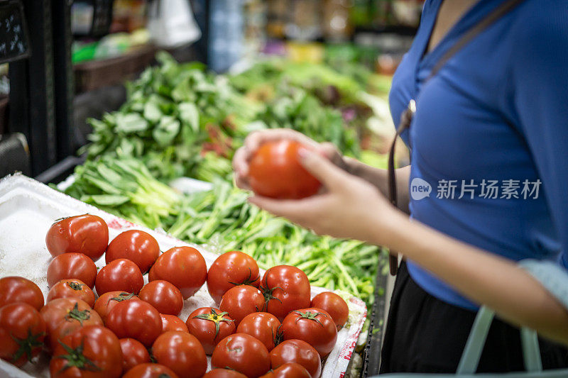 一位年轻女子在超级市场挑选西红柿