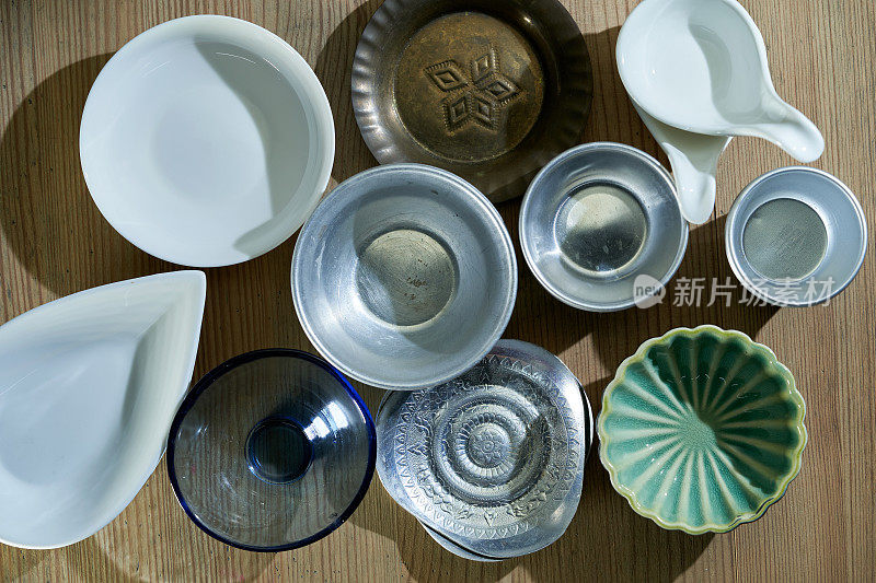 成堆的陶瓷盘子和餐具在木头背景上的顶部视图